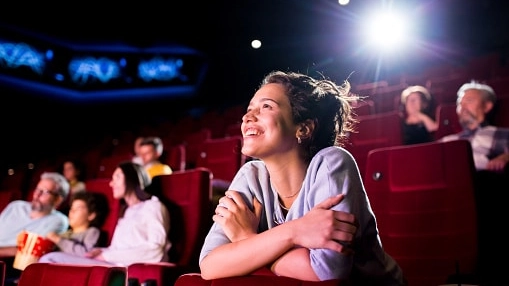 Girl watching a movie at the cinema and enjoying.