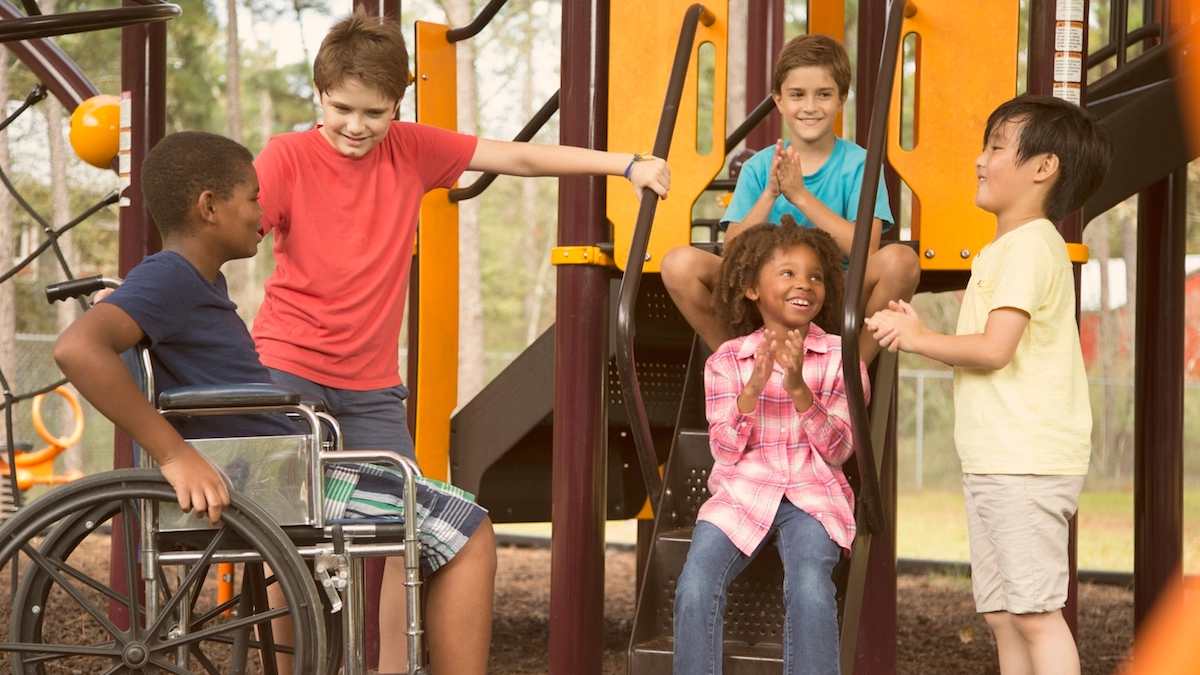 Multi-ethnic group of school children on school playground, one wheelchair.