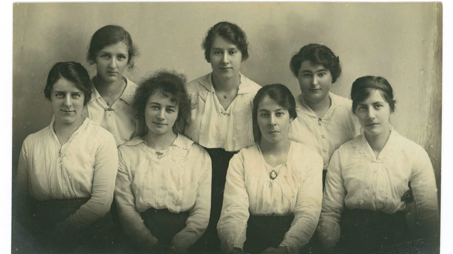 Original WW1 era portrait, group of pretty young women, all of similar age, in their late teens or early twenties, quite possibly college students, maybe teacher training, probably from the middle classes. They wear their hair up in chignon bun hairstyles