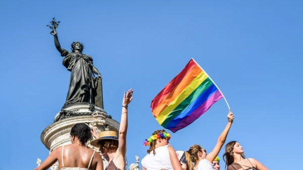 A young woman waves a rainbow flag high during the Gay Pride parade in Paris, France.