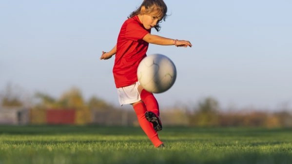 Girl kicks a soccer ball on a soccer field