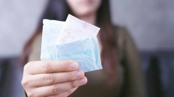 A woman carries a sanitary napkin, she is menstrual, focus hand