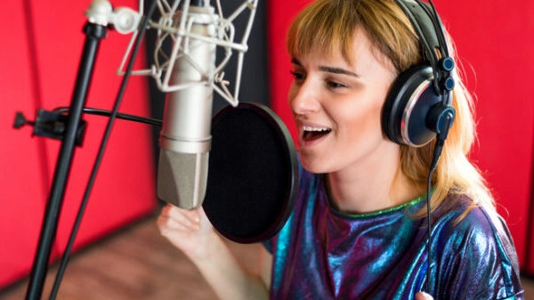 Female with microphone recording a voice for dubbing in music studio