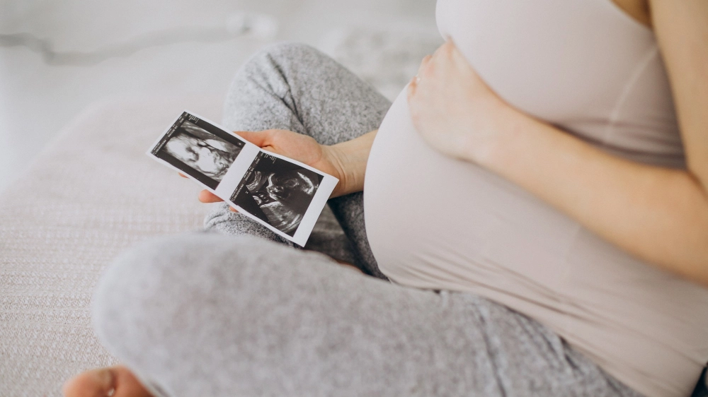 donna-incinta-con-foto-ad-ultrasuoni-seduta-sul-letto