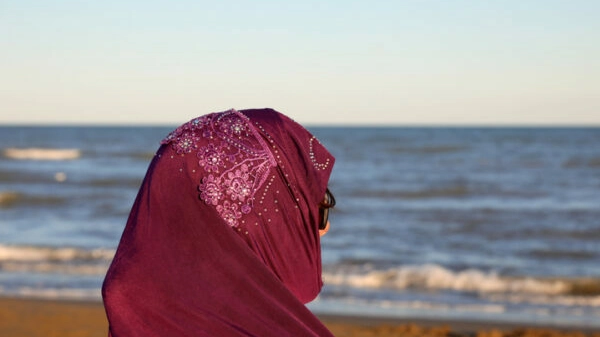 girl with arabic veil to cover her head by the sea at sunset