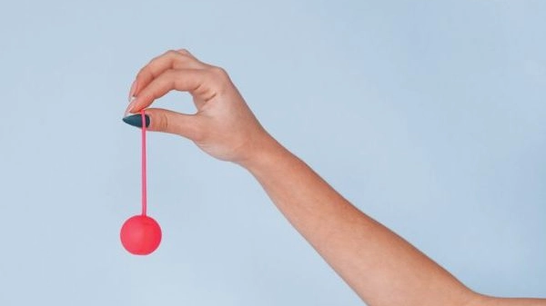 Woman's hands with pink sex ball against studio background