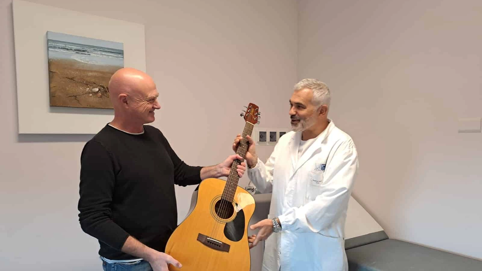 Il medico e musicista Stefano Antonelli consegna la chitarra al direttore del reparto di oncologia Andrea Mambrini