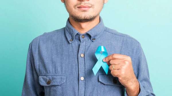 handsome man posing he holding light blue ribbon for supporting people living