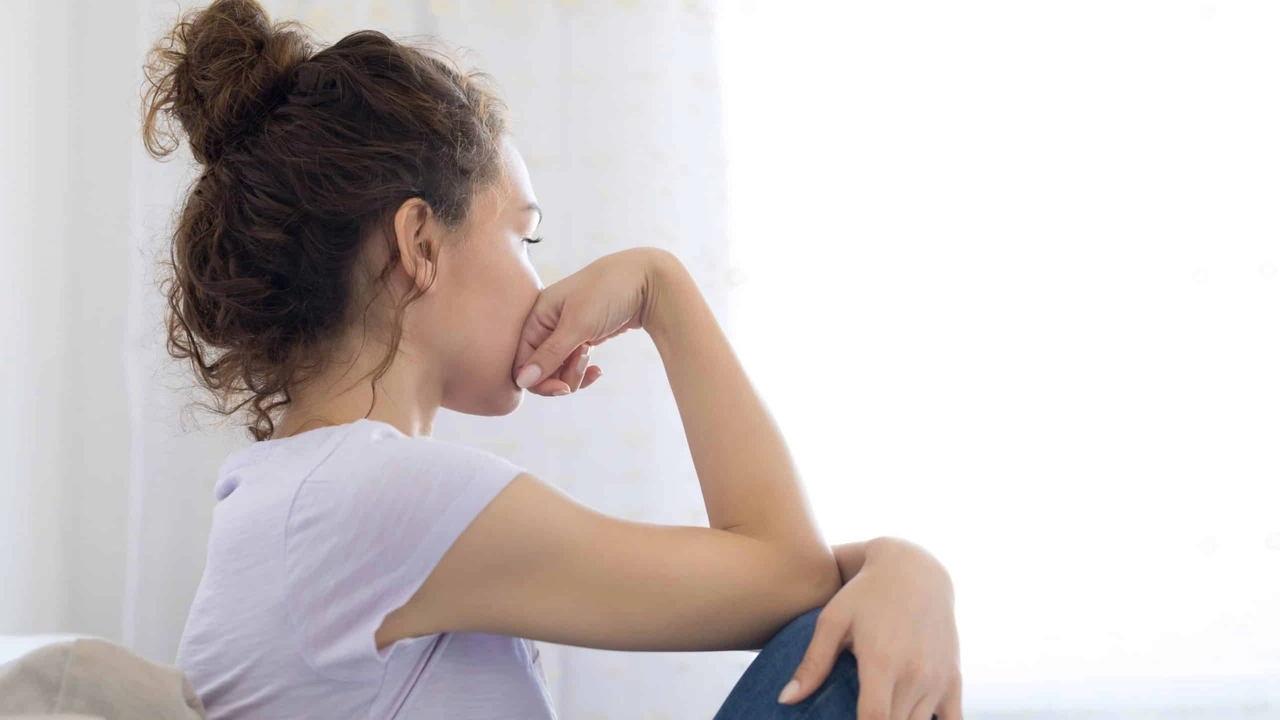 Sad woman sitting on couch alone