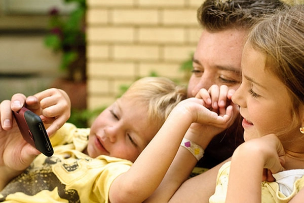 Un papà al cellulare coi figli