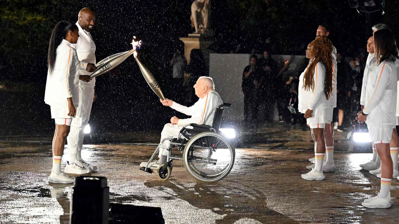 Il centenario Charles Coste consegna la fiamma olimpica agli ultimi due tedofori, Marie-Jose Perec e Teddy Riner (Photo by MOHD RASFAN / AFP)