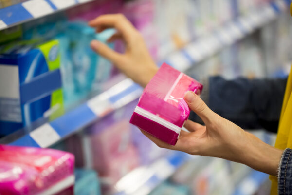 Unrecognizable woman is choosing between pad and tampon in the store, selective focus