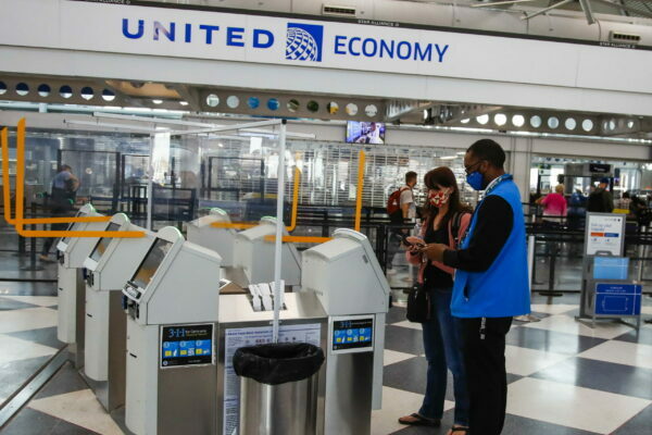 epa09533225 A United Airlines customer service representative (R) assists a passenger (L) check in at O'Hare International Airport in Chicago, Illinois, USA, 19 October 2021. United Airlines parent company, United Airlines Holdings, Inc., reported a less than expected third quarter loss of 1.02 US dollars per share which was lower than analysts predictions of a loss of 1.67 US dollars Revenues are reported at 7.75 billion US dollars.  EPA/TANNEN MAURY