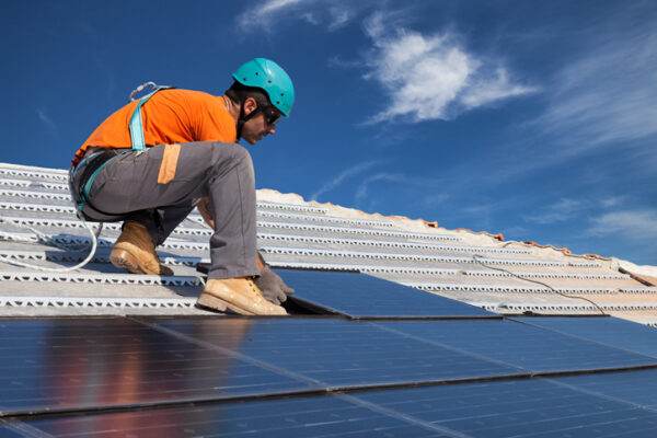 Man during intallation of alternative energy photovoltaic solar panels on roof