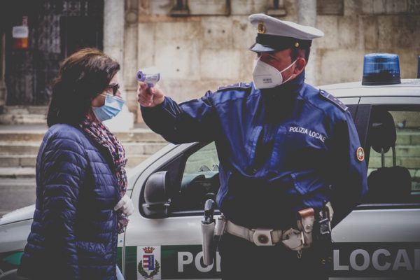 Cremona, Lombardy, Italy - 13 th may 2020 - Local police officer measuring adultÂ  woman body temperature with infrared thermometer scanner while in line to access open food market
