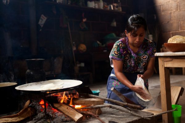 Zinacantan, Mexico - May 10, 2014: A traditional Mayan Tzotzil woman makes corn tortillas for tourists in her home in Zinacantan, Chiapas, Mexico.