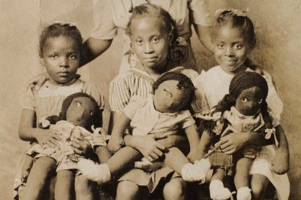 Nello scatto anonimo datato 1943, ’Bambine con bambole di stoffa nera’, stampa in gelatina d’argento