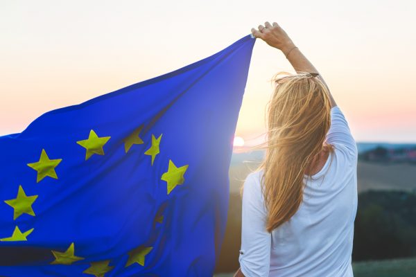Woman holding European Union flag at sunset.