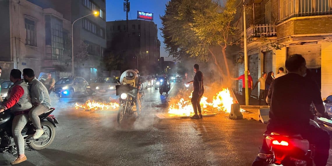 Un'immagine degli scontri tra manifestanti e forze armate a Teheran (Photo by AFP)