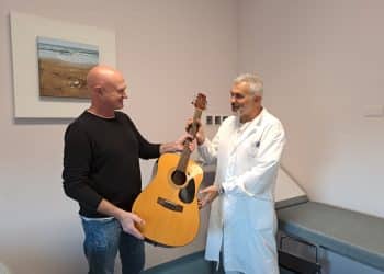 Il medico e musicista Stefano Antonelli consegna la chitarra al direttore del reparto di oncologia Andrea Mambrini