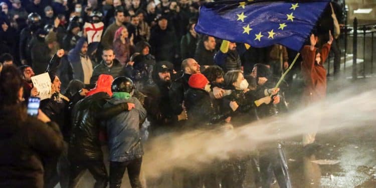 Nana Malashkia, 44 anni, sventola la bandiera dell'Europa  di fronte alla polizia georgiana, che risponde con gli idranti (AFP)